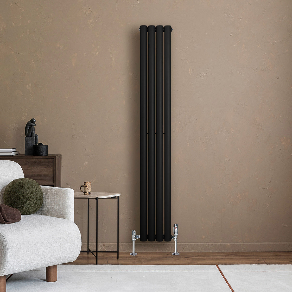 Oval svart enkelkolonnsradiator med fyra vertikala sektioner, placerad mot en beige vägg i ett modernt rum med en soffa och ett bord