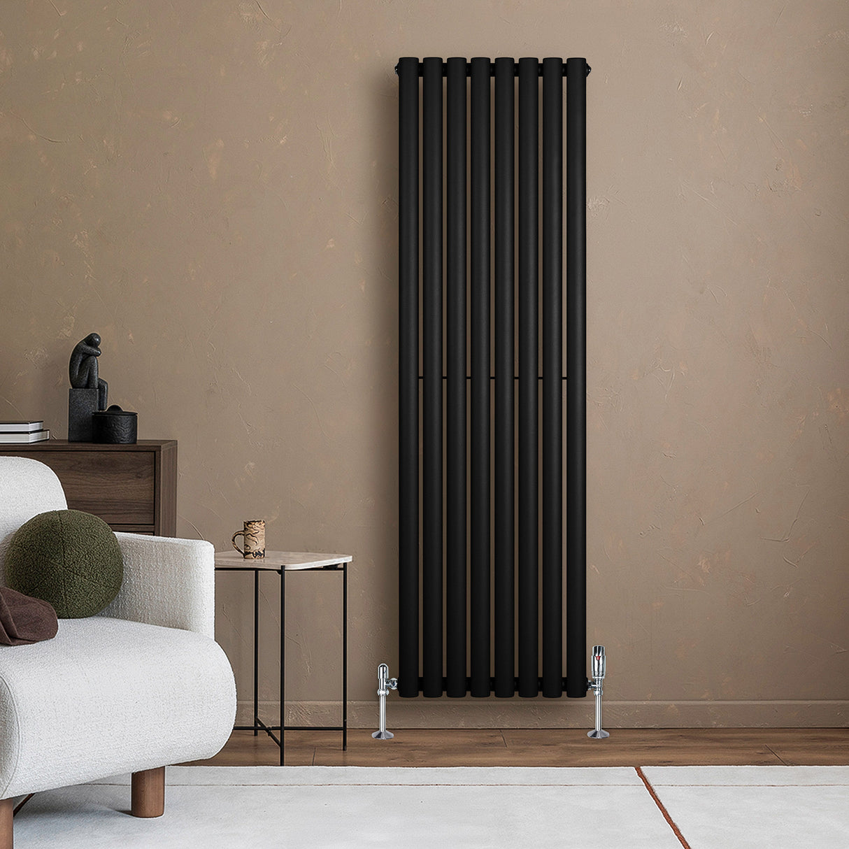 Svart oval enkelkolonnsradiator med släta ytor, monterad på en beige vägg, omgiven av en modern inredning och möbler