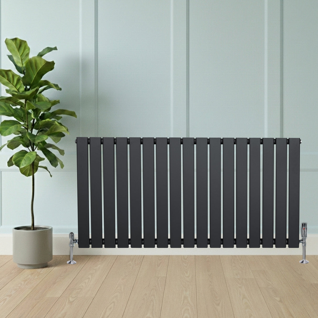 Platt enkelkolumnsradiator i antracitgrå med släta ytor och vertikala lameller, placerad framför en grön växt i kruka