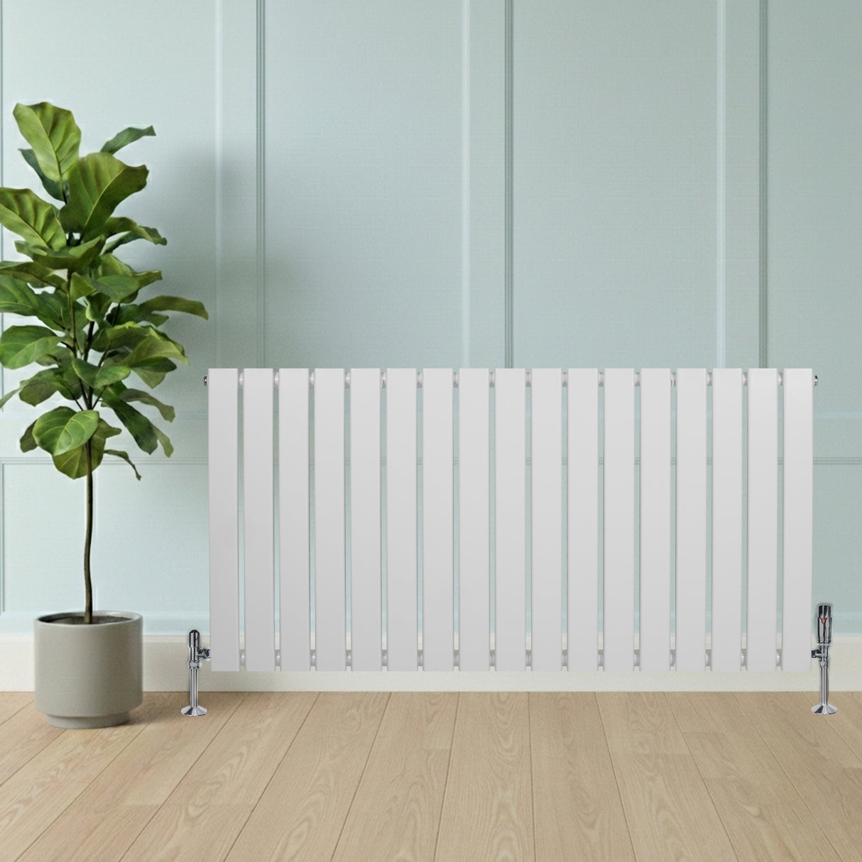 Platt enkelkolumnsradiator i vit färg med släta ytor och ventiler, placerad framför en växt i en modern inredning