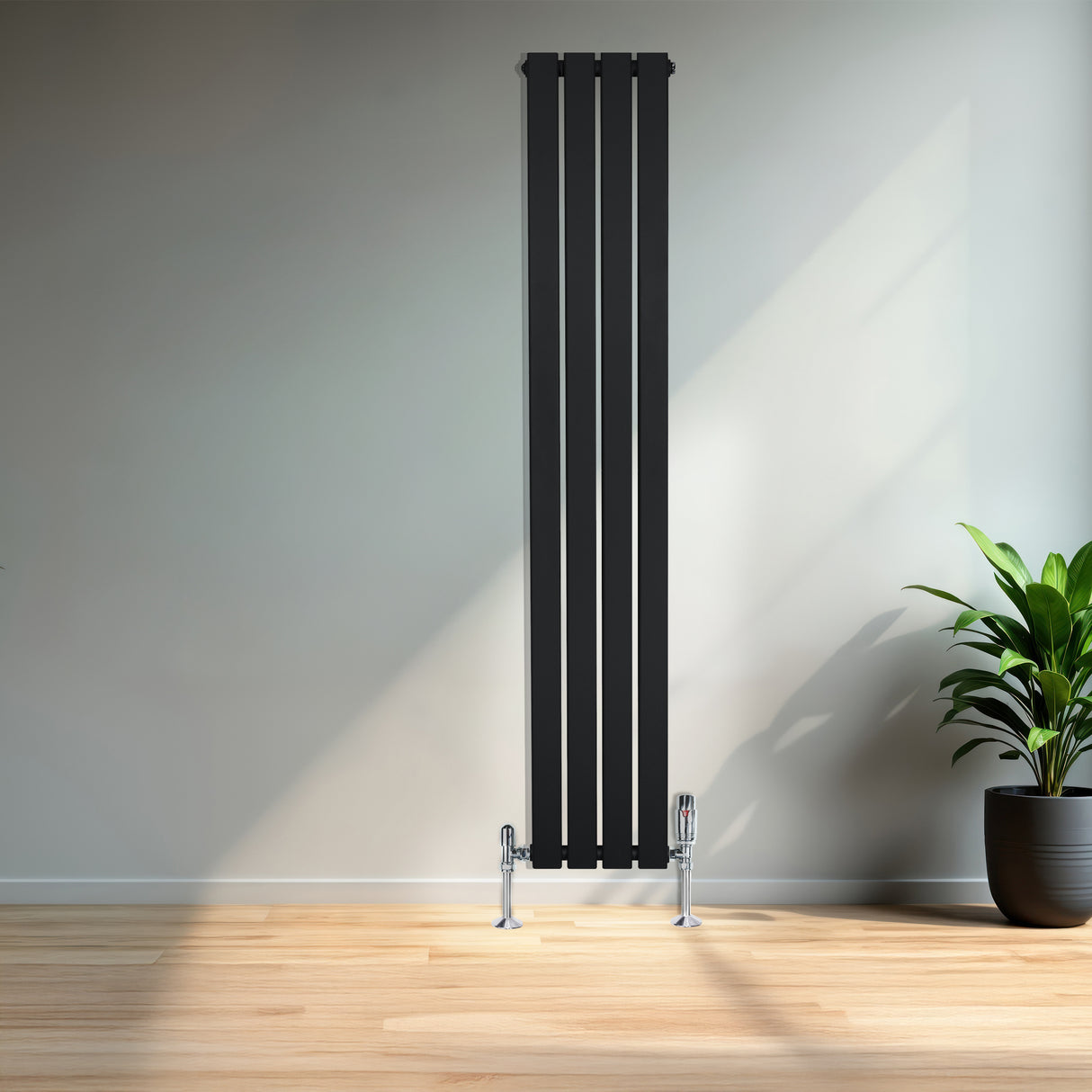 Svart platt enkelkolumnsradiator med ventiler, 1600 mm x 280 mm, placerad mot en ljus vägg med en grön växt i kruka bredvid