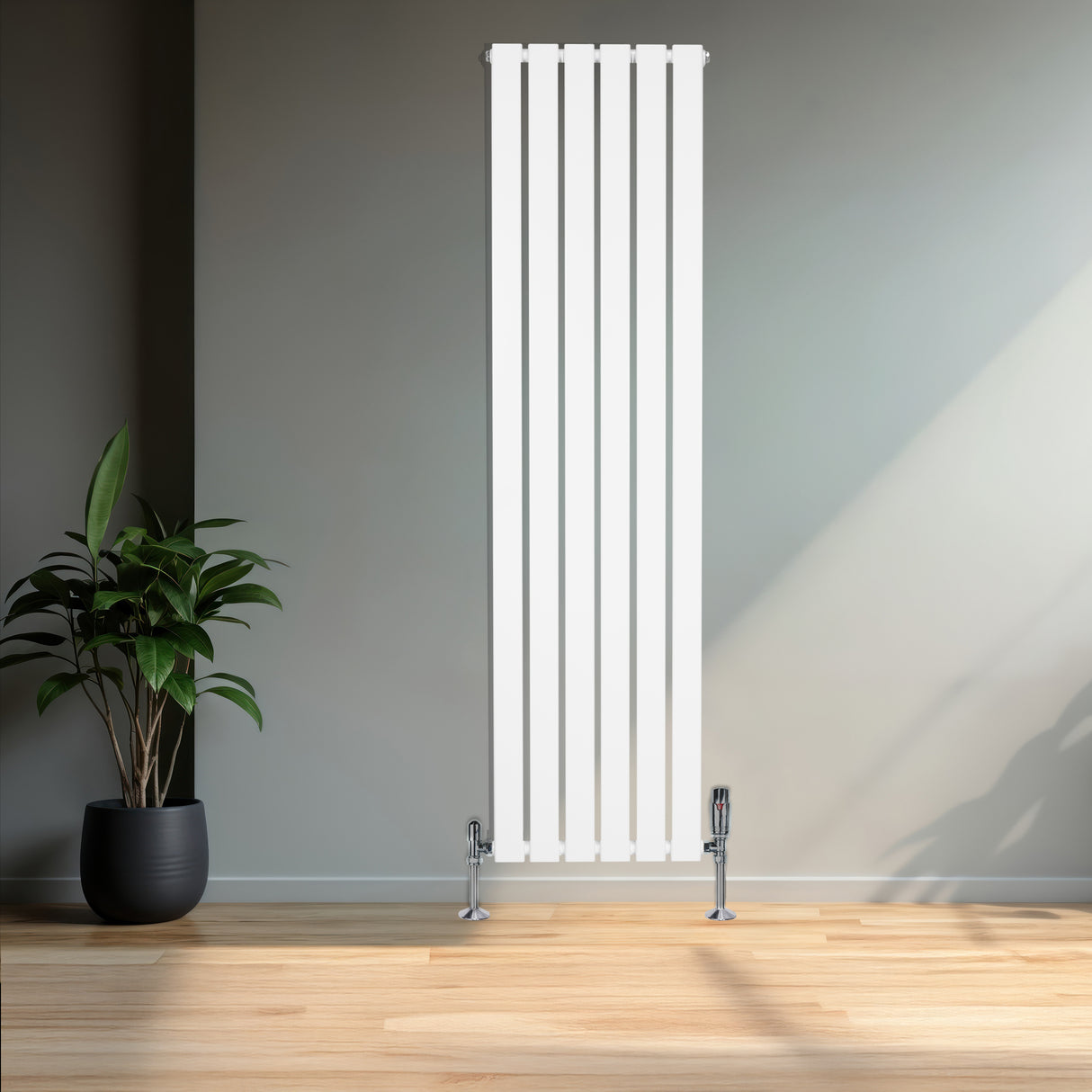 Vit platt enkelkolumnsradiator med ventiler, 1600 mm x 420 mm, placerad mot en grå vägg med en grön växt i kruka i förgrunden