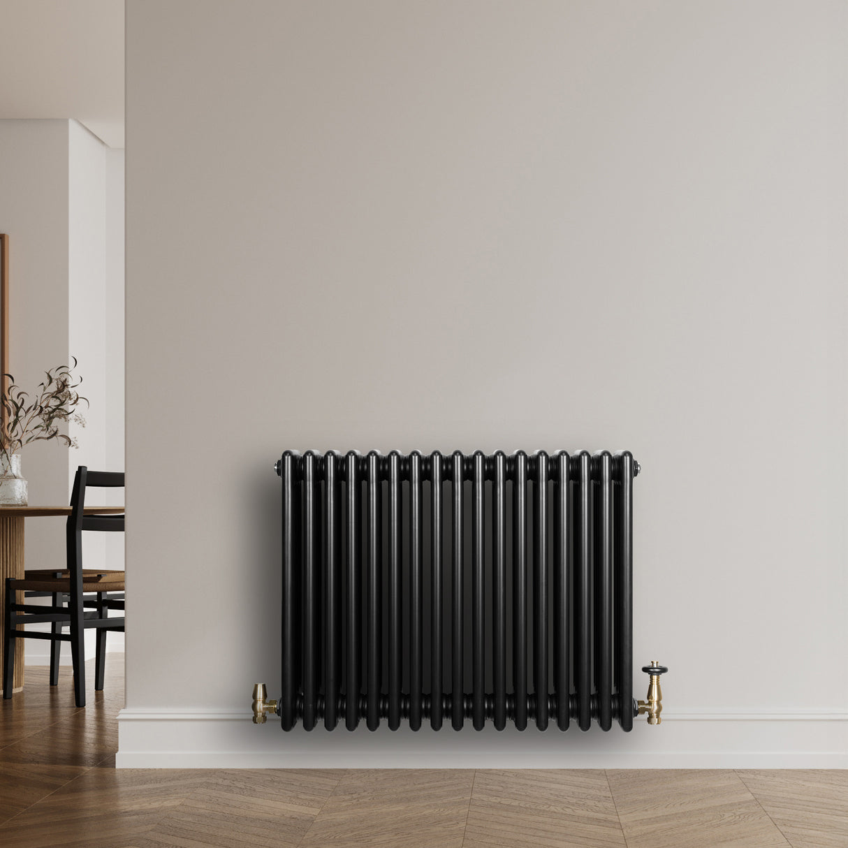 Svart traditionell 4-kolonnsradiator i metall med glänsande yta, placerad mot en ljus vägg i en modern inredning