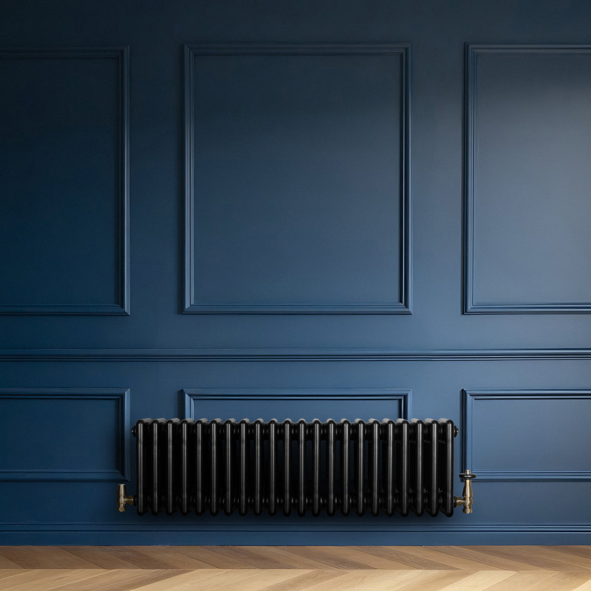 Svart traditionell 4-kolonnsradiator i metall, placerad mot en mörkblå vägg, med eleganta detaljer och en slät yta