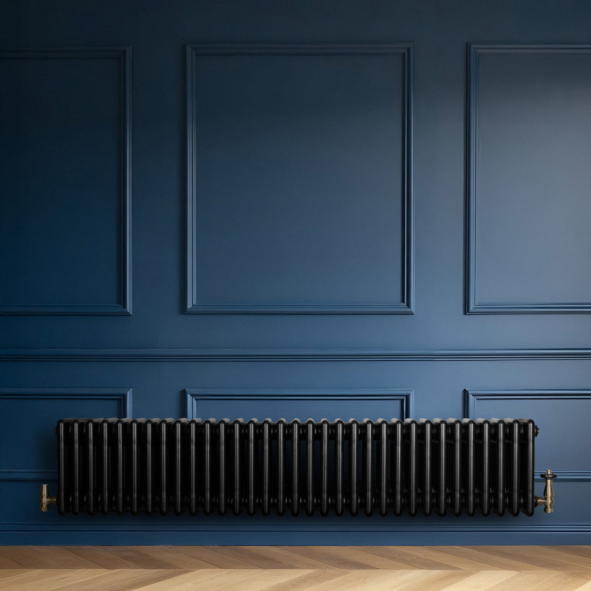 Svart traditionell 4-kolonnsradiator i metall, 300 x 1505 mm, installerad på en blå vägg med elegant träparkettgolv