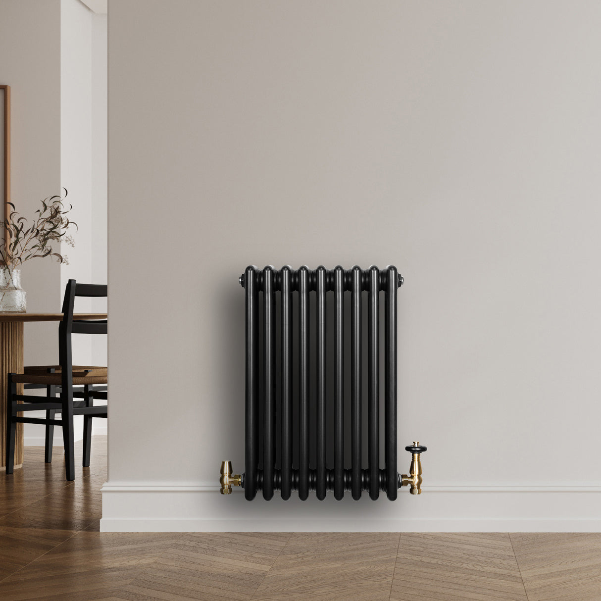 Svart traditionell 4-kolonnsradiator i metall, med släta ytor och glänsande mässingsventiler, placerad mot en ljus vägg