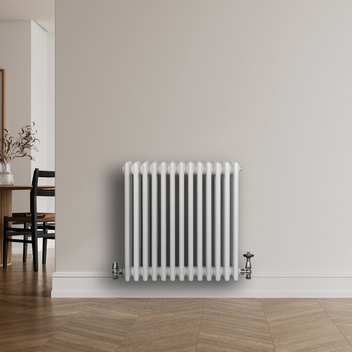 Vit traditionell 4-kolonnsradiator med släta ytor och kromade ventiler, placerad mot en ljus vägg i ett modernt rum