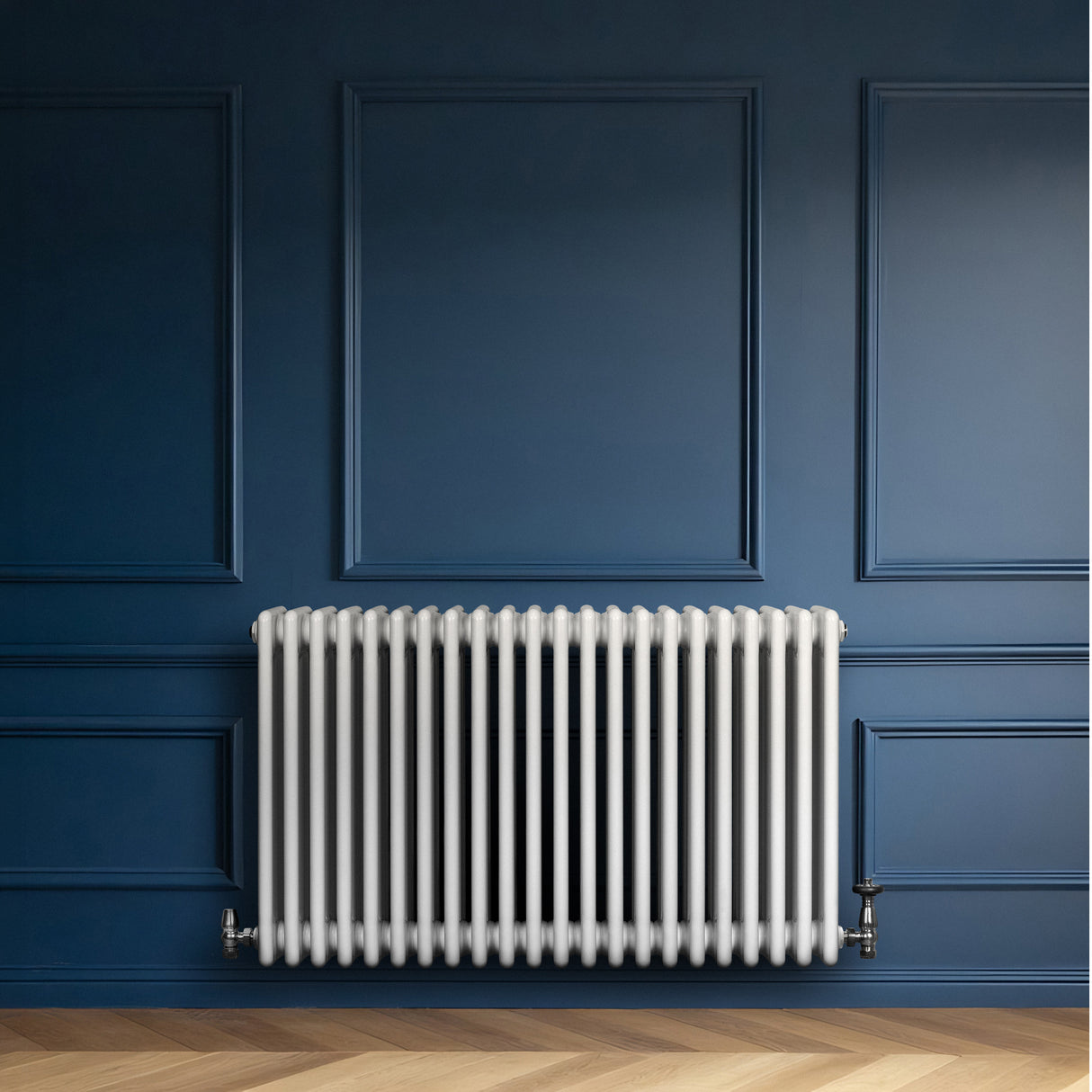Traditionell vit 4-kolonnsradiator i metall, 600 x 1010 mm, monterad på en blå vägg med träparkettgolv, elegant och stilren design
