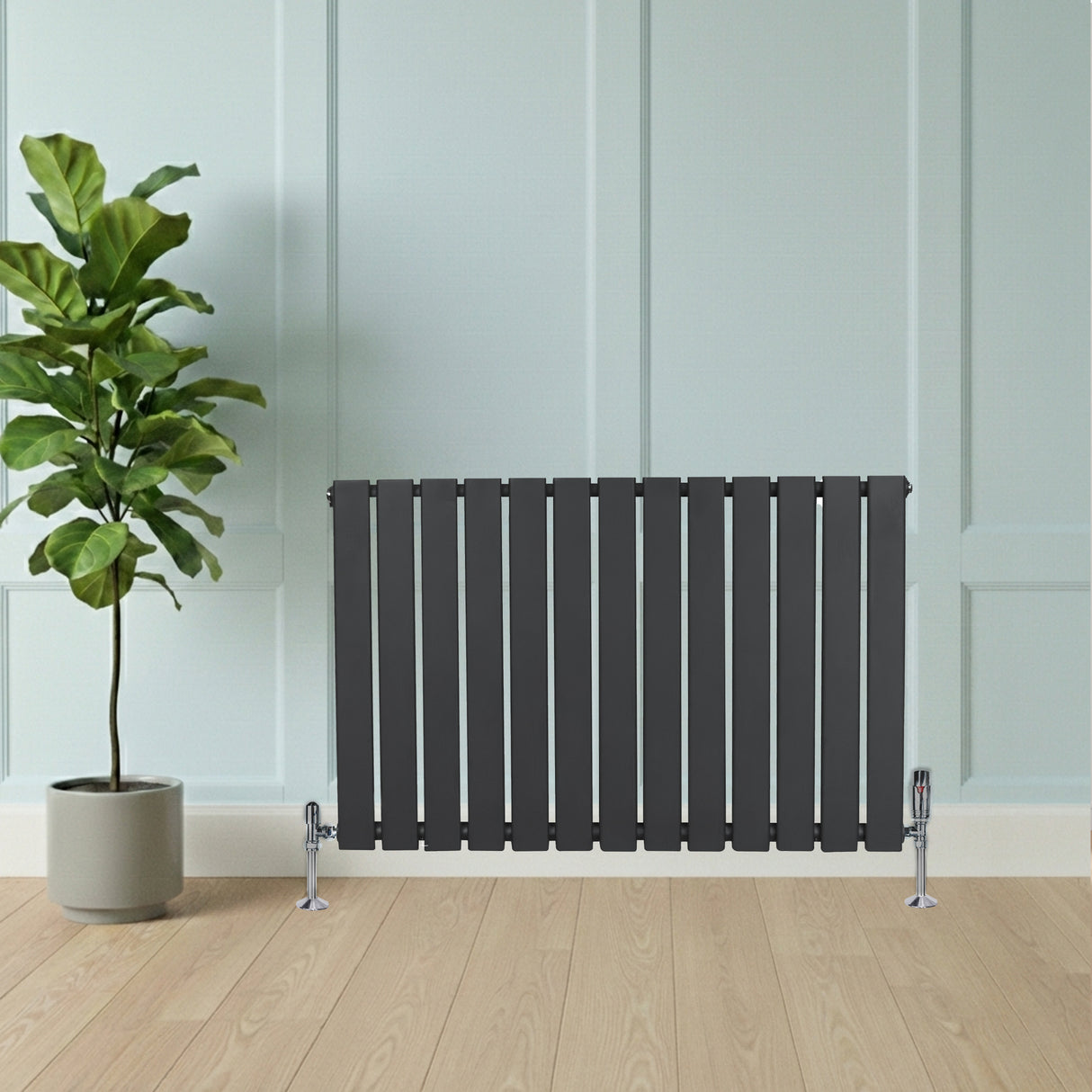 Platt enkelpelarradiator i antracitgrå, 600 x 910 mm, med släta ytor och stilren design, placerad framför en grön växt