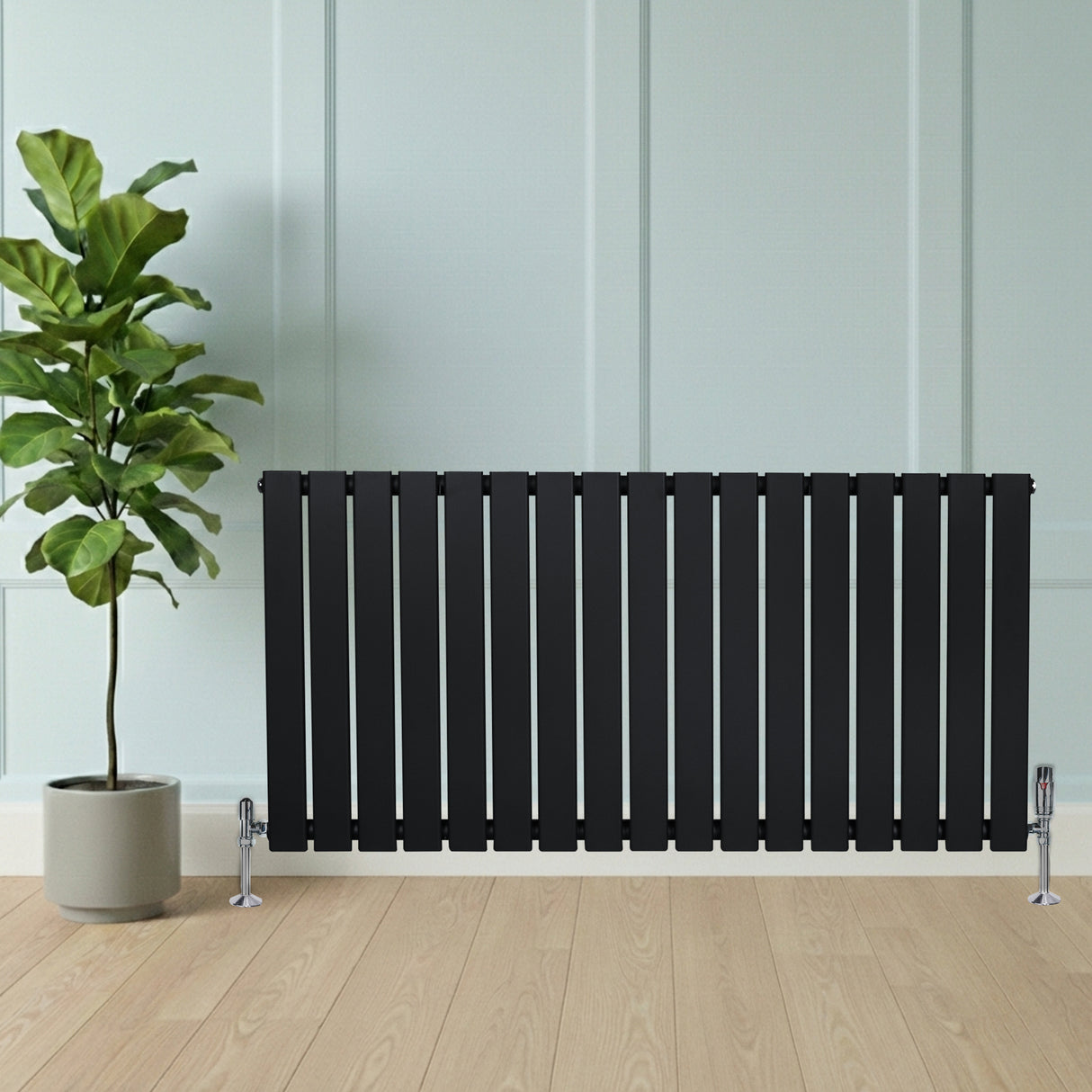 Svart platt enkelpelarradiator med släta, vertikala ribbor, placerad framför en grön växt i en modern inredning med trälookgolv