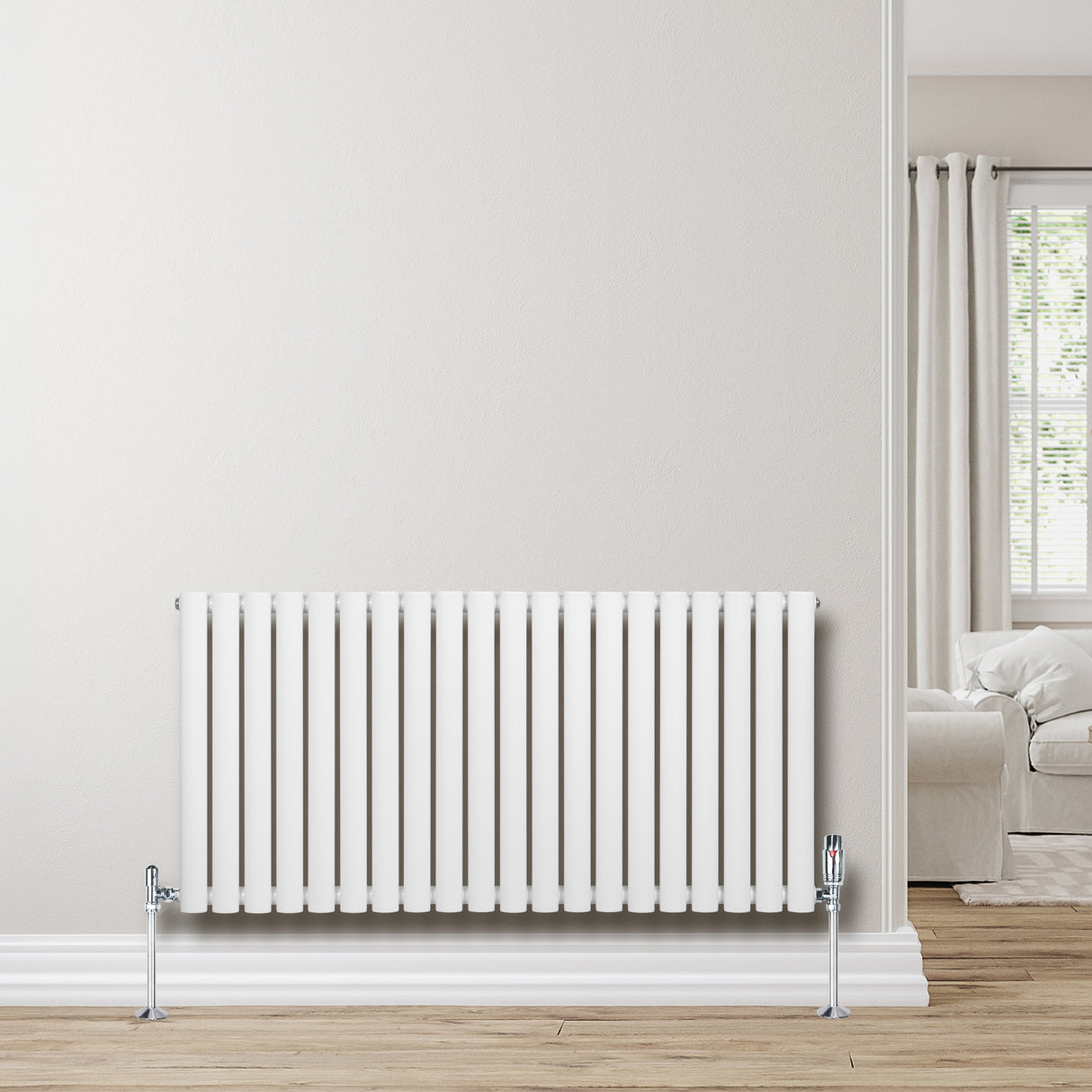 Oval enkelpelarradiator i vit färg, 600 x 1200 mm, med släta ytor och kromade ventiler, placerad mot en ljus vägg i ett modernt rum