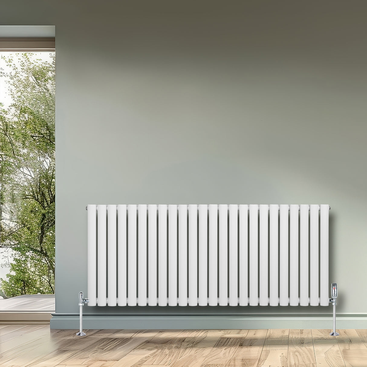 Oval enkelpelarradiator i vit färg, 600 x 1440 mm, med släta ytor och stilren design, placerad mot en grön vägg och fönster