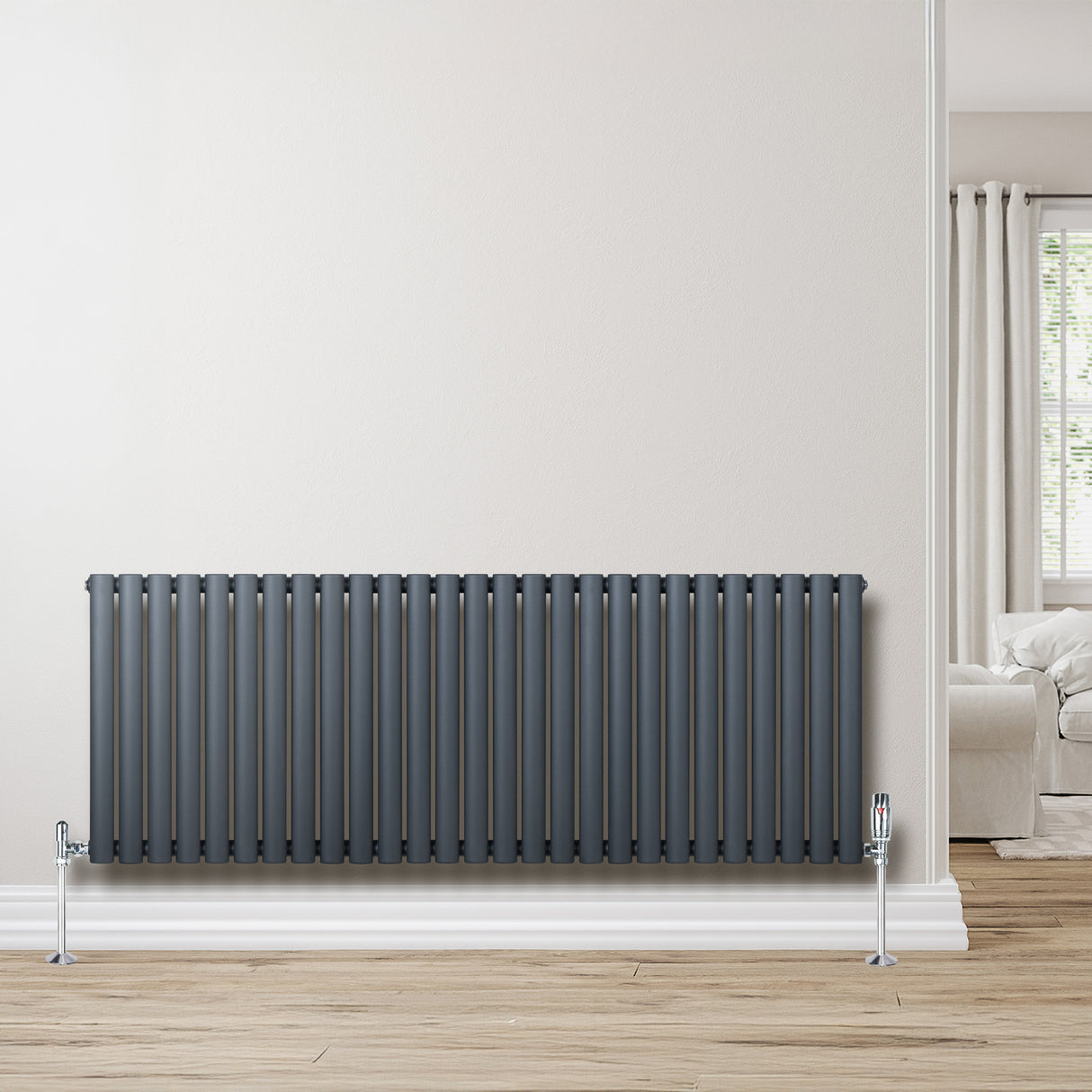 Oval enkelpelarradiator i antracitgrå, 600 x 1620 mm, med släta ytor och vertikala ribbor, placerad mot en ljus vägg