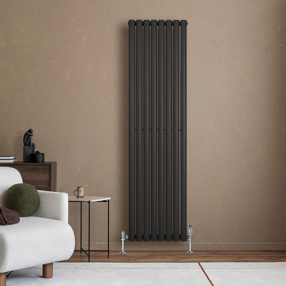 Oval svart enkelpelarradiator i modern design, 1800 x 480 mm, placerad mot en beige vägg, med stiliga ben och minimalistisk inredning