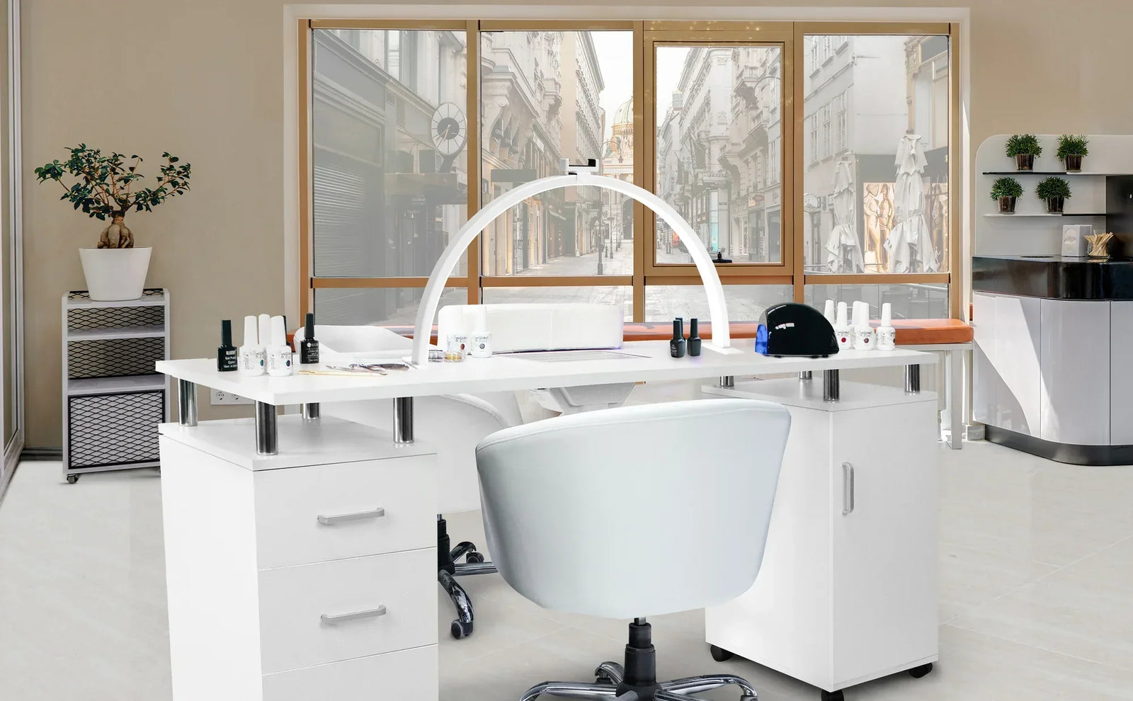 Vitt nagelbord med ergonomisk stol, nagellack och salongsutrustning i en modern, ljus salong med stora fönster