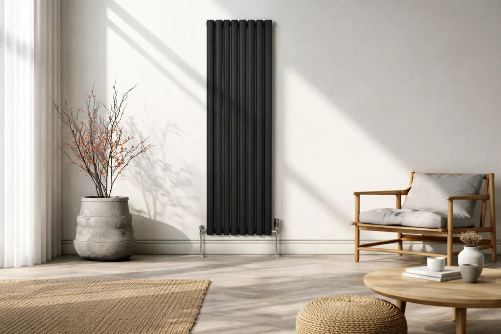 Svart pelarradiator med vertikala ribbor, placerad mot en ljus vägg i ett modernt rum med naturligt ljus och stilren inredning