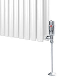 Förkromad termostatventil för radiator, glänsande yta, rundad form, monterad på en vit radiator med vertikala ribbor
