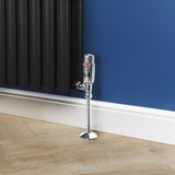 Förkromad termostatventil för radiator, glänsande yta, elegant design, placerad vid en svart radiator mot en blå vägg