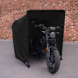 Svart motorcykel skyddad av en svart tältliknande struktur, med en modern design och kraftfulla linjer, placerad på en grå asfalt yta