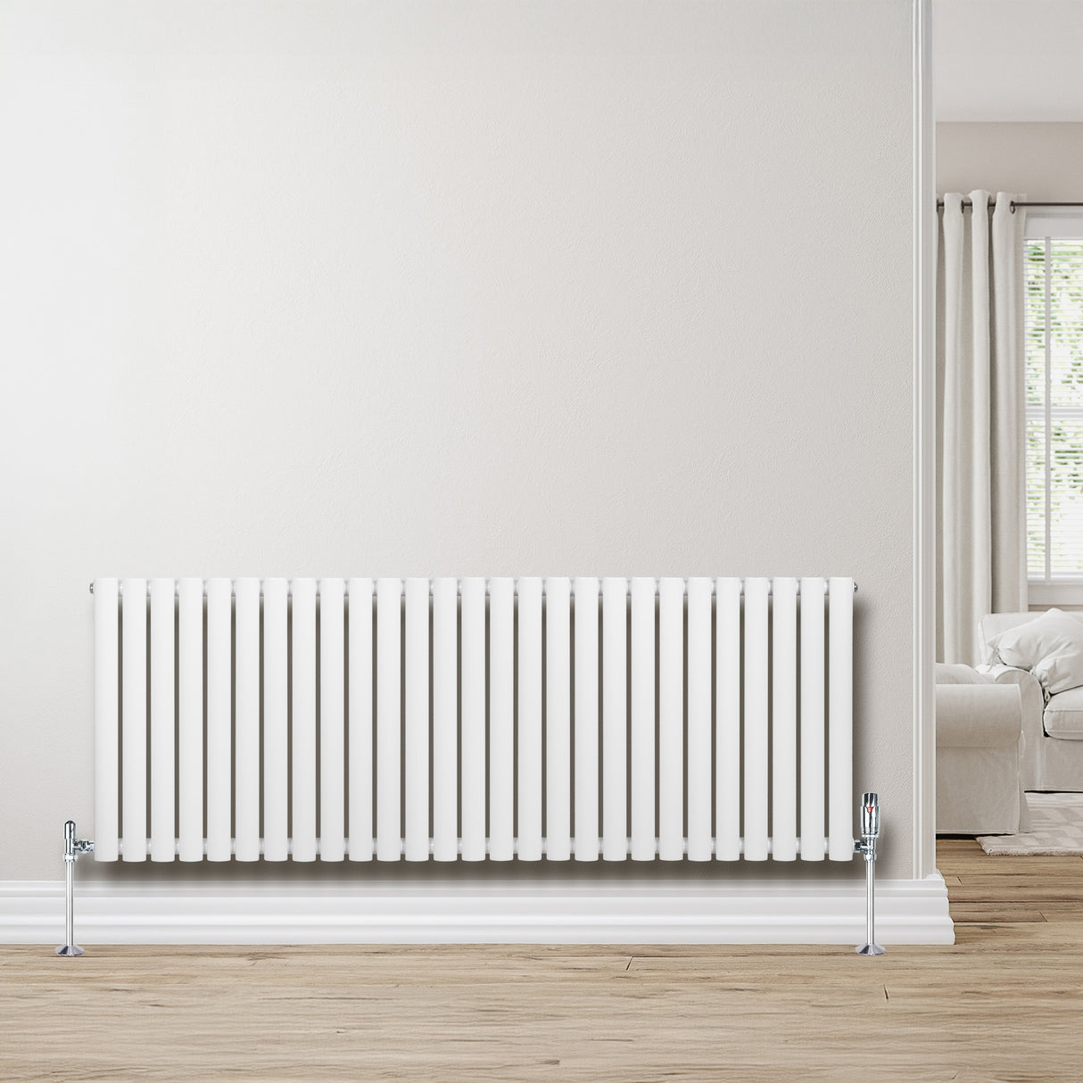 Oval vit enkelpelarradiator med släta ribbor, 600 mm x 1620 mm, monterad på vägg i ett ljust rum med trägolv och fönster