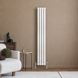 Oval vit enkelkolonnsradiator med fyra vertikala rör, placerad mot en beige vägg, kompletterad med moderna ventiler och stilren inredning