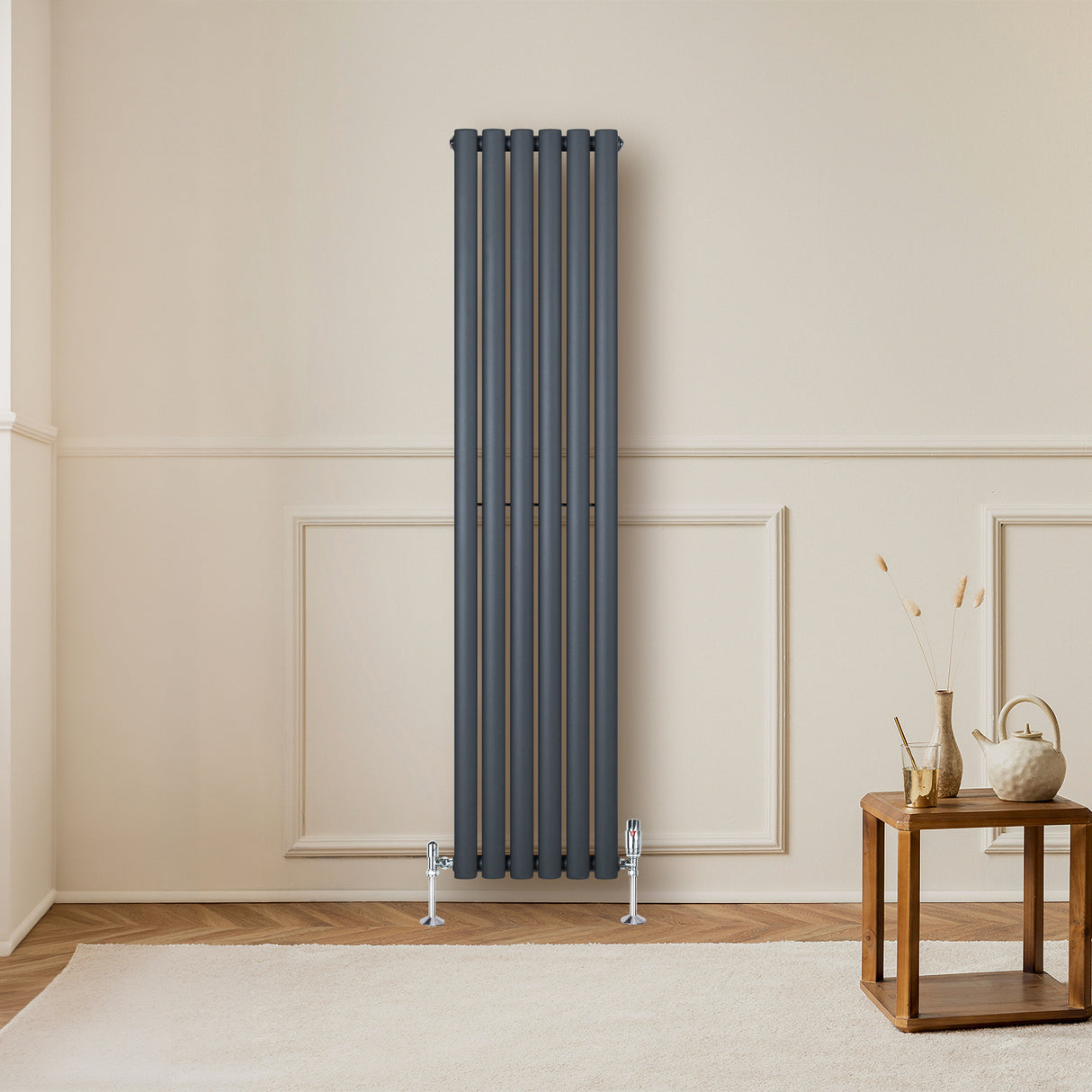Oval enkelkolonnsradiator i antracitgrå, 1600 mm x 360 mm, med släta ytor och moderna ventiler, placerad mot en ljus vägg