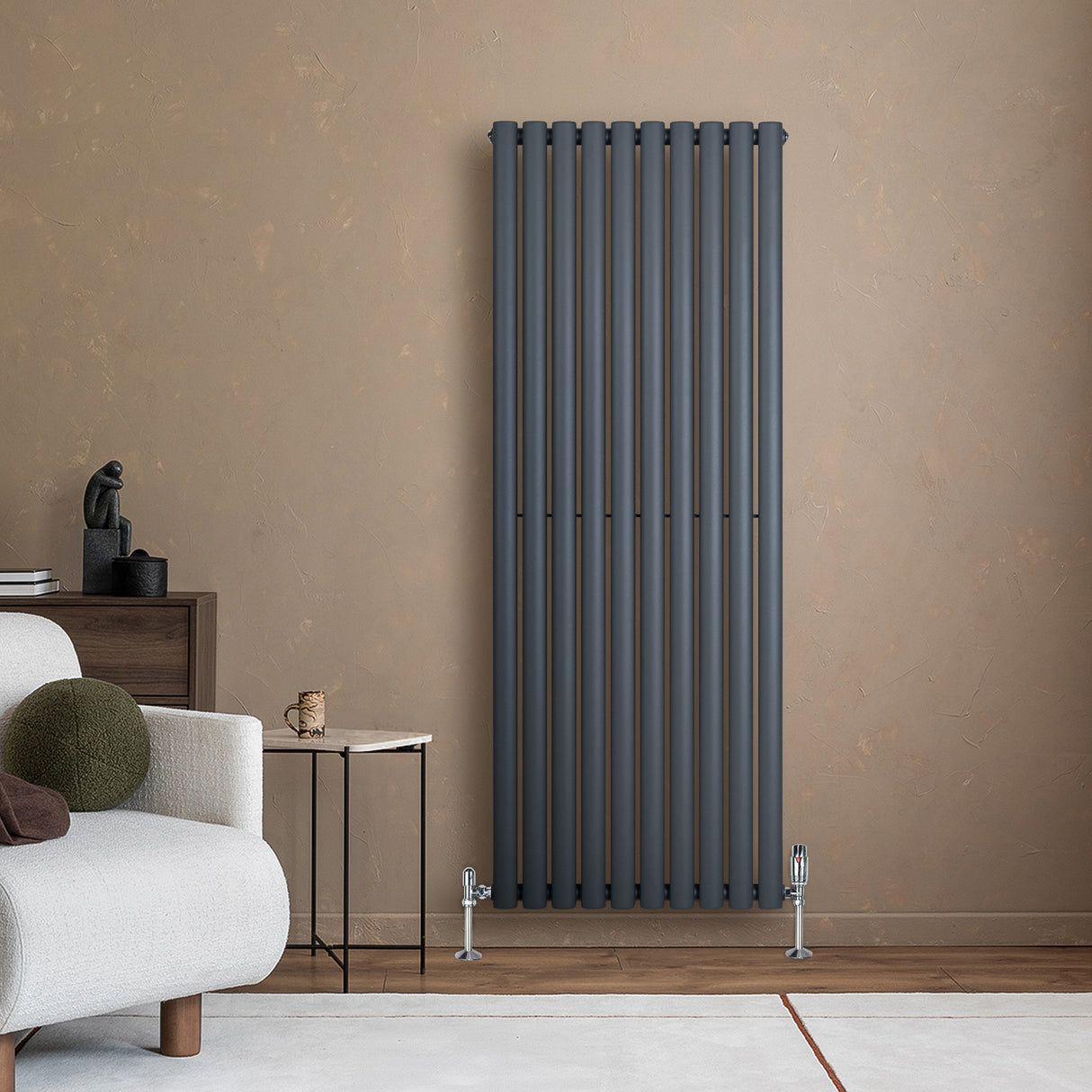 Oval enkelkolonnsradiator i antracitgrå, 1600 mm x 600 mm, med släta, vertikala rör och stilren design mot en beige vägg