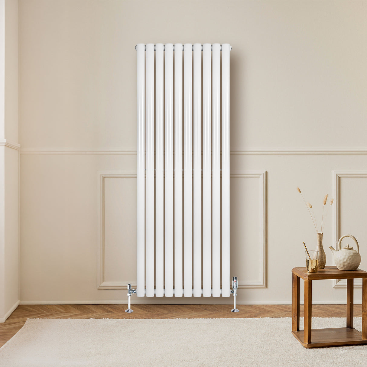 Oval vit enkelpelarradiator med släta, glänsande ytor, placerad på en ljus vägg, med en träbänk och inredning i rummet