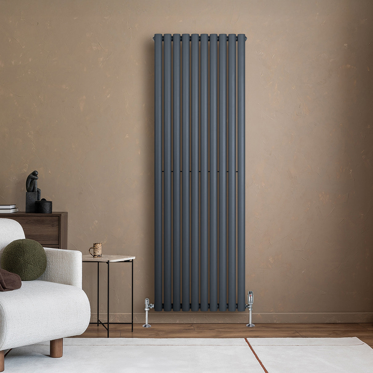 Oval enkelkolonnsradiator i antracitgrå, 1800 mm x 600 mm, med släta ytor och moderna ventiler, placerad mot en beige vägg