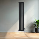 Svart platt enkelkolumnsradiator med ventiler, 1600 mm x 280 mm, placerad mot en ljus vägg med en grön växt i kruka bredvid