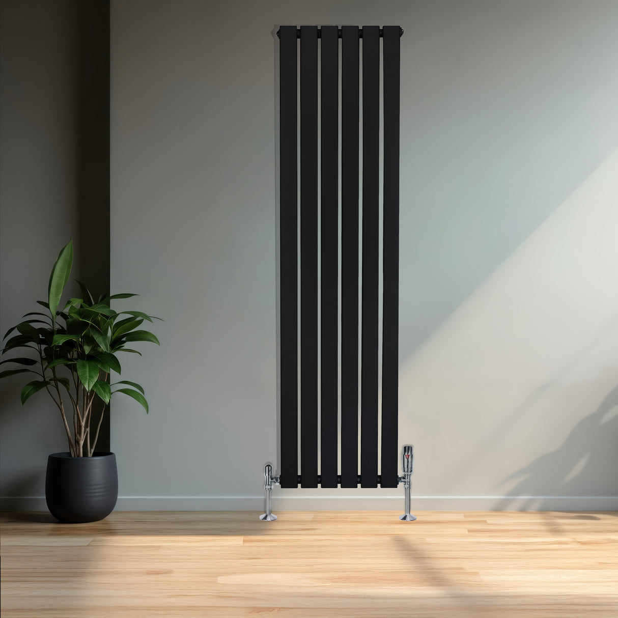 Svart platt enkelkolumnsradiator med ventiler, 1600 mm x 420 mm, placerad mot en ljus vägg med en grön växt i kruka i förgrunden