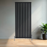 Svart platt enkelkolumnsradiator med ventiler, 1600 mm x 700 mm, placerad på en ljus trägolv i ett modernt rum med växt