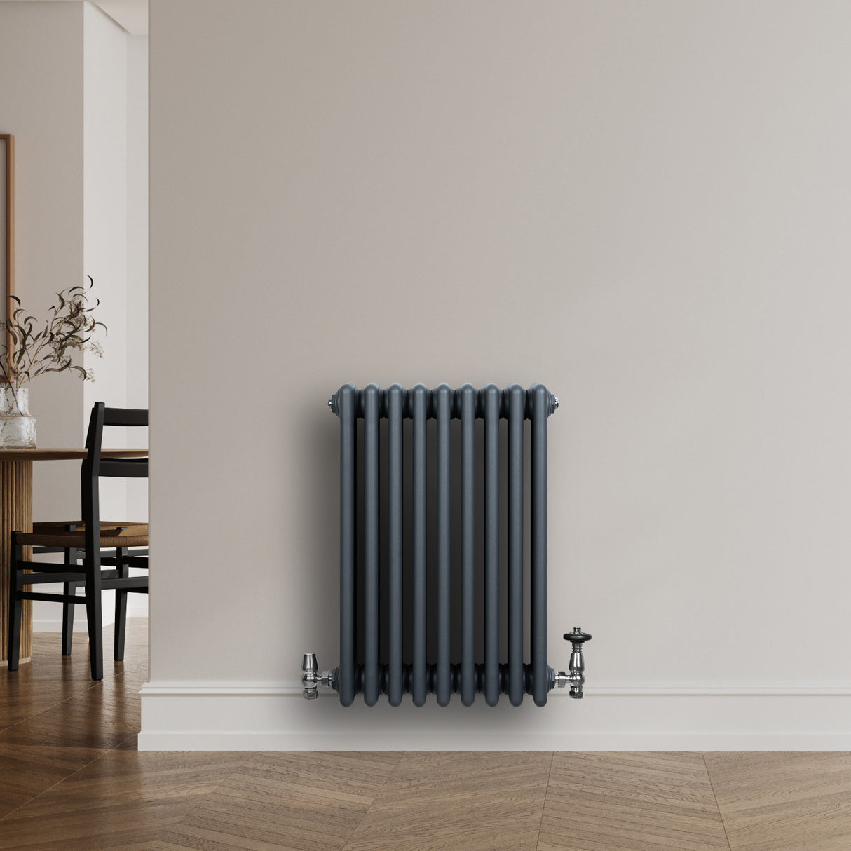 Traditionell antracitgrå 4-kolonnsradiator med släta ytor och ventiler, monterad på en ljus vägg i ett modernt rum