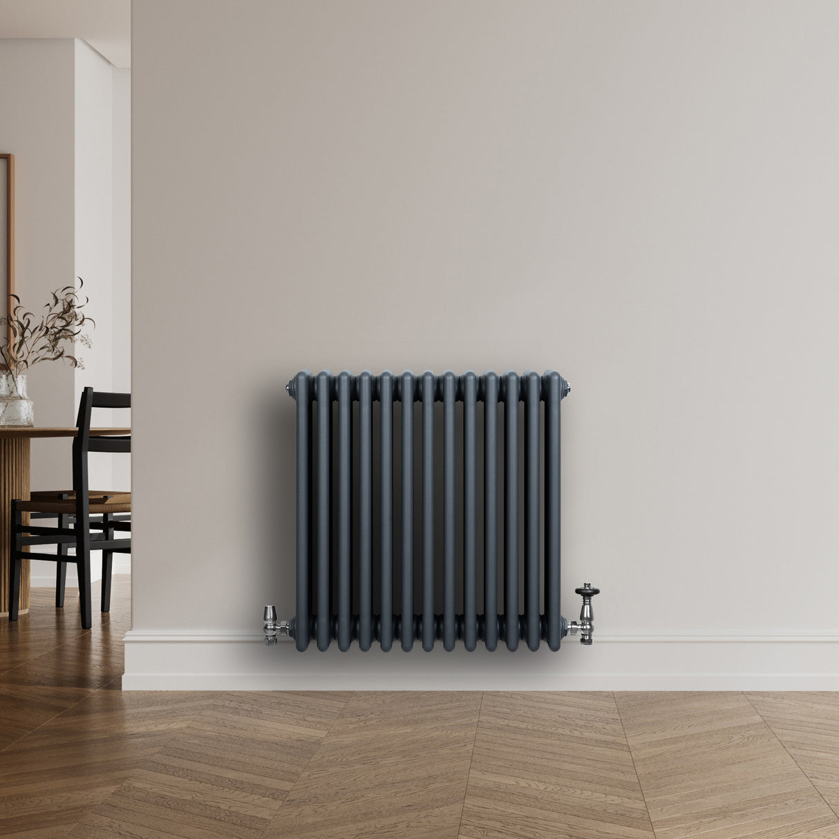 Traditionell antracitgrå 4-kolonnsradiator med släta ytor och ventiler, placerad mot en ljus vägg i ett modernt rum