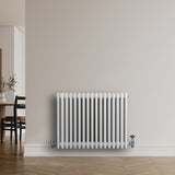 Traditionell vit 4-kolonnsradiator med släta ytor, monterad på vägg, perfekt för att ge värme och stil till rummet