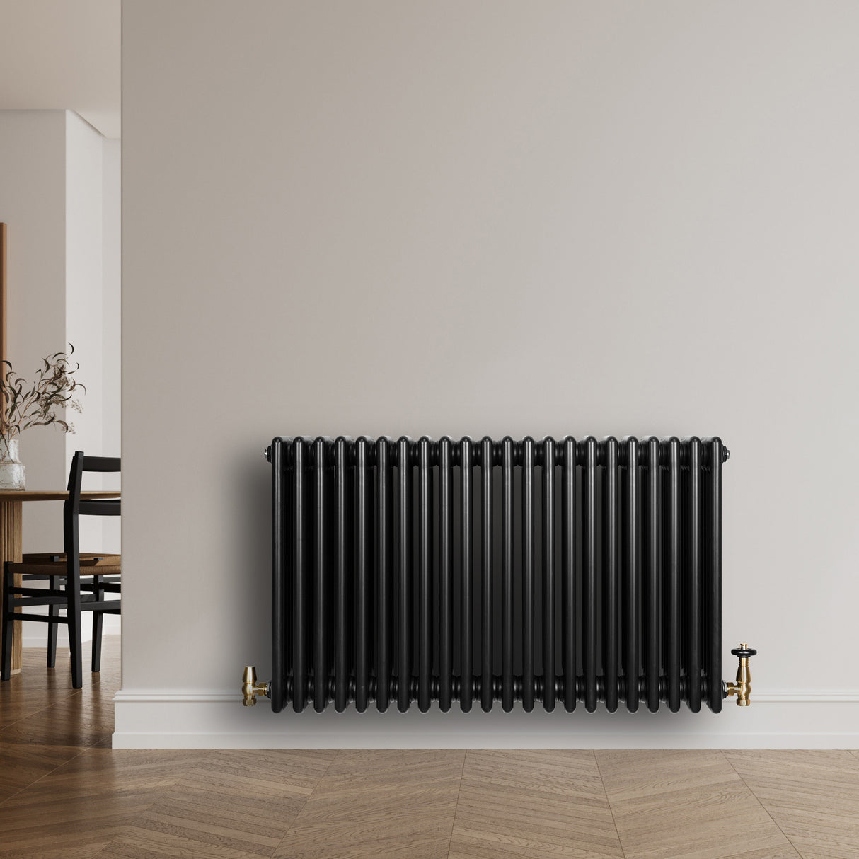 Svart traditionell 4-kolonnsradiator med glänsande yta, placerad mot en ljus vägg, med synliga ventiler i mässing