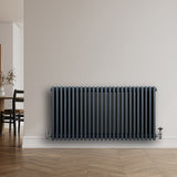 Traditionell 4-kolonnsradiator i antracitgrå, 600 x 1190 mm, med släta ytor och rundade kanter, placerad mot en vägg