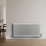 Traditionell vit 4-kolonnsradiator i metall, 600 x 1190 mm, med släta ytor och synliga ventiler, placerad mot en ljus vägg