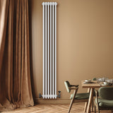 Vit traditionell 4-kolonnsradiator med släta ytor, monterad på vägg, omgiven av en varm beige vägg och elegant inredning