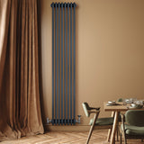 Traditionell antracitgrå 4-kolonnsradiator med ventiler, installerad på vägg, omgiven av en varm, beige inredning och trädetaljer