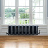 Traditionell 4-kolonnsradiator i antracit med släta, runda sektioner, placerad under ett stort fönster i ett ljust rum