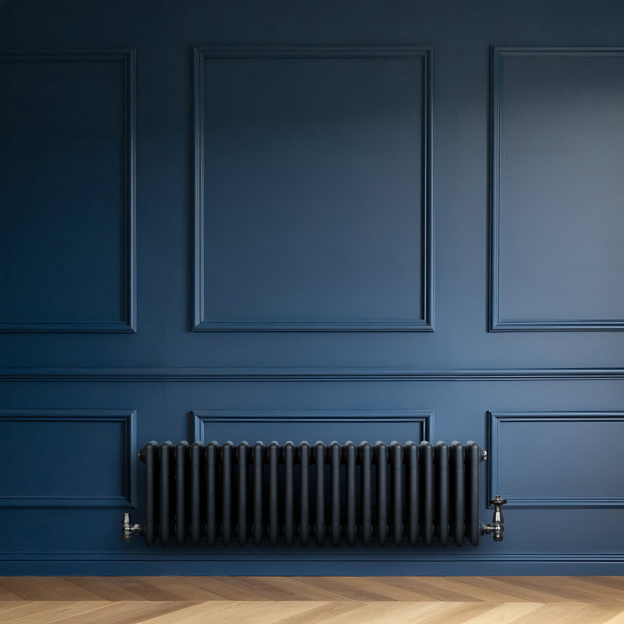 Traditionell 4-kolonnsradiator i antracit, placerad mot en blå vägg med eleganta paneler och ett mörkt trägolv