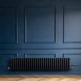 Traditionell 4-kolonnsradiator i antracit, med släta, runda sektioner och elegant design, placerad mot en mörkblå vägg