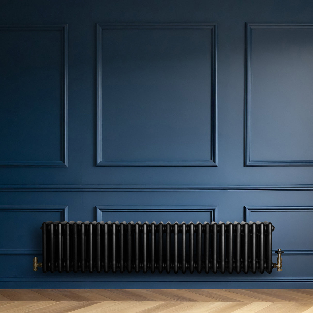 Traditionell svart 4-kolonnsradiator i metall, placerad mot en mörkblå vägg, med eleganta detaljer och en slät yta