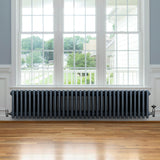 Traditionell 4-kolonnsradiator i antracit, 300 x 1505 mm, med släta ytor och rundade kanter, placerad under ett stort fönster