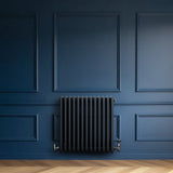 Traditionell 4-kolonnsradiator i antracitgrå, med släta ytor och en elegant design, placerad mot en mörkblå vägg