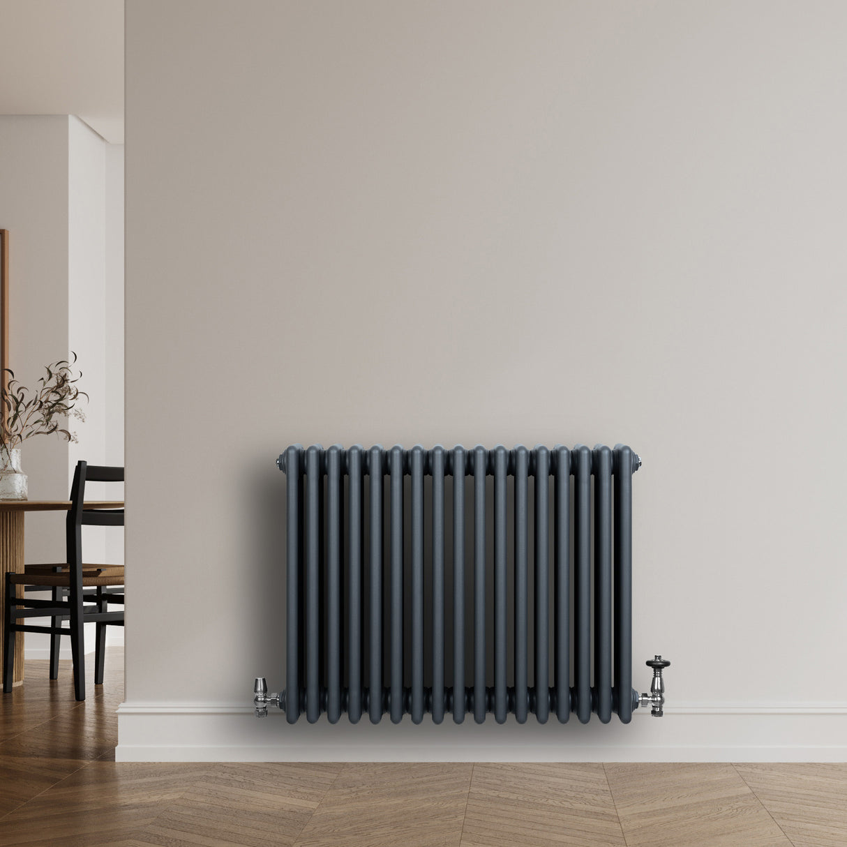 Traditionell 4-kolonnsradiator i antracitgrå, med släta ytor och vertikala rör, monterad på en vit vägg i ett modernt rum