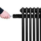 Svart traditionell 4-kolonnsradiator med en hand som rengör den med en borste, synlig struktur och släta ytor