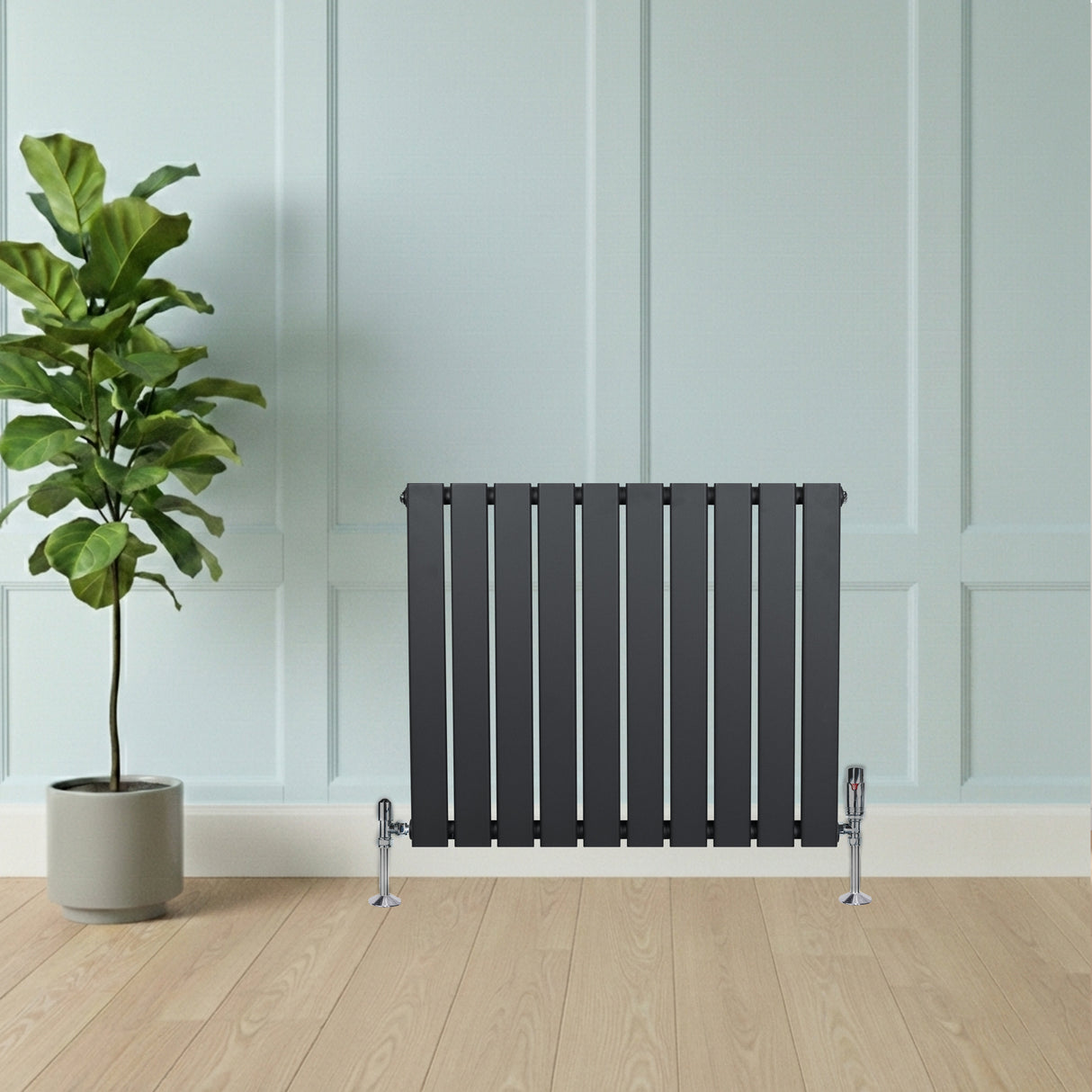 Platt antracitgrå enkelpelarradiator med släta, vertikala lameller, placerad mot en ljus vägg och träliknande golv