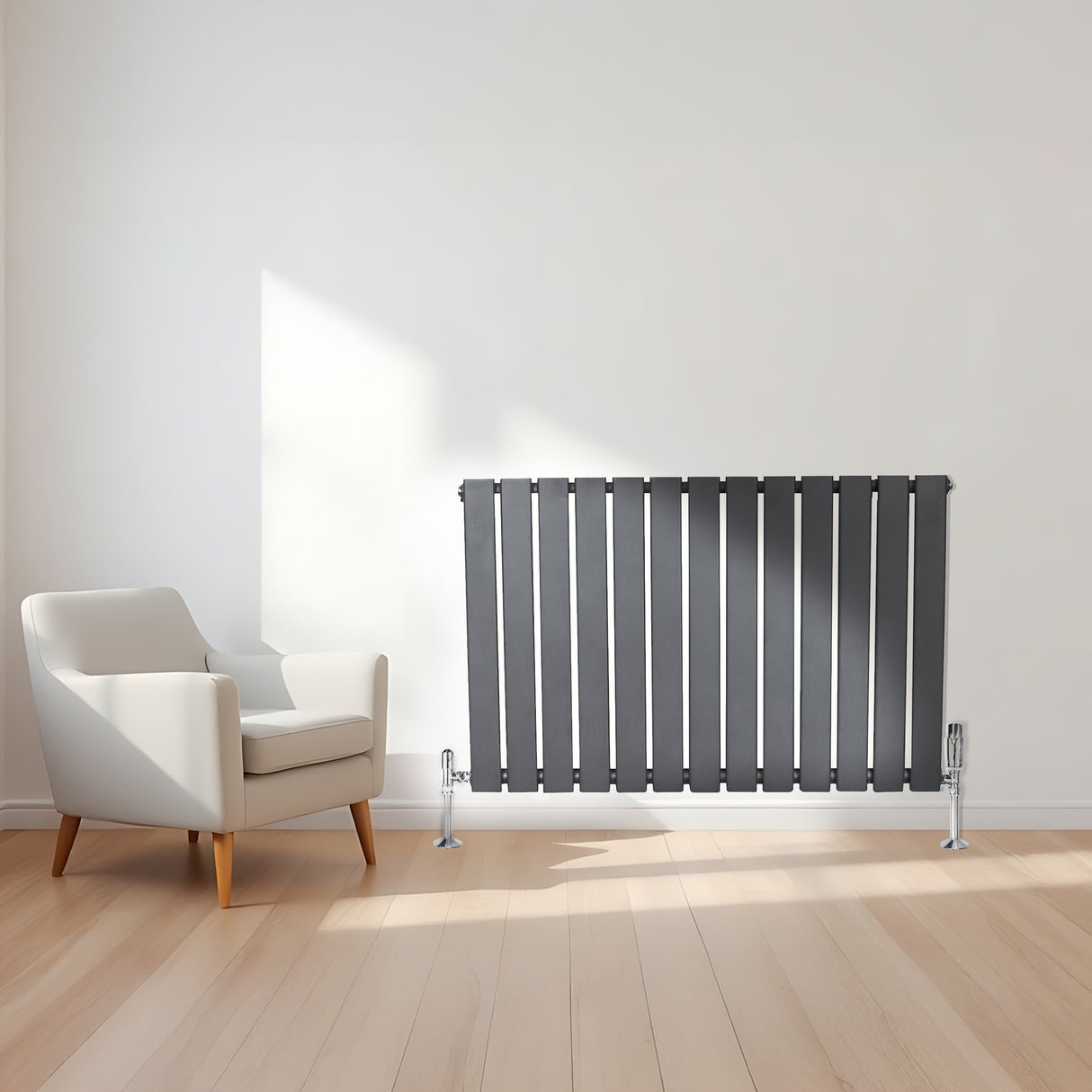 Platt antracitgrå enkelpelarradiator med släta, vertikala ribbor, placerad på en ljus träparkett framför en vit vägg